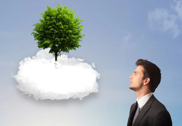 Joven señalando a un árbol verde en la parte superior de una nube blanca — Foto de Stock