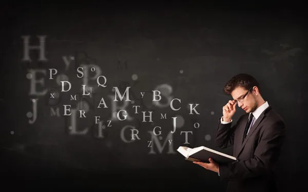 Young man reading a book with alphabet letters — Stock Photo, Image