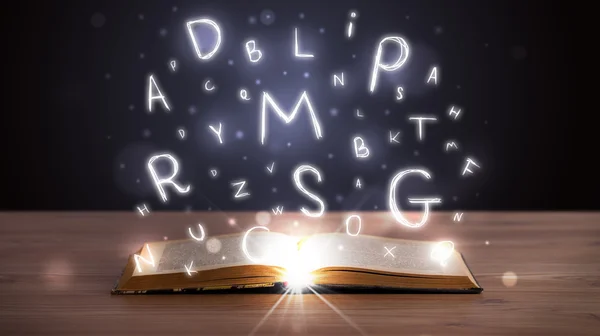 Libro abierto con letras brillantes volando — Foto de Stock