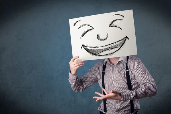 Affärsman hålla ett papper med smileyn framför hans hea — Stockfoto