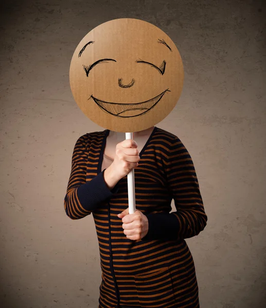 Young woman holding a smiley face board — Stock Photo, Image