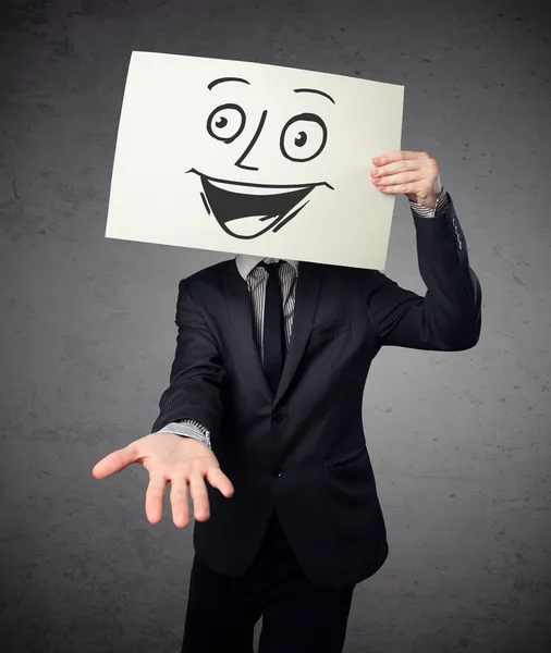 Empresário segurando um papelão com rosto sorridente na frente — Fotografia de Stock