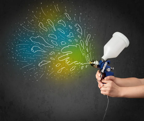 Worker with airbrush gun paints colorful lines and splashes — Stock Photo, Image