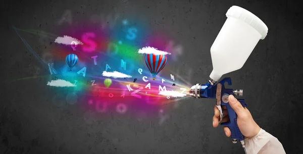 Worker with airbrush and colorful abstract clouds and balloons — Stock Photo, Image