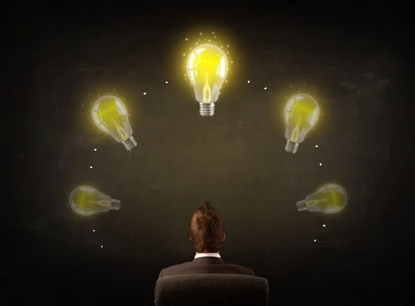 Businessman sitting with lightbulbs over his head — Stock Photo, Image