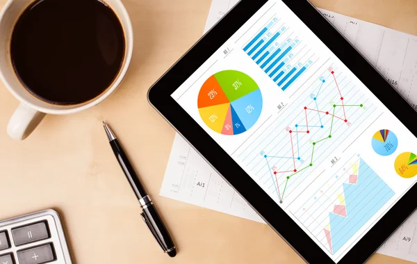 Tabletta pc mutatja diagramok a képernyőn egy csésze kávé az asztalon — Stock Fotó