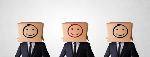 Handsome men in suit gesturing with drawn smiley faces on box — Stock Photo, Image