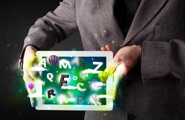 Young person showing tablet with abstract letters and sky — Stock Photo, Image