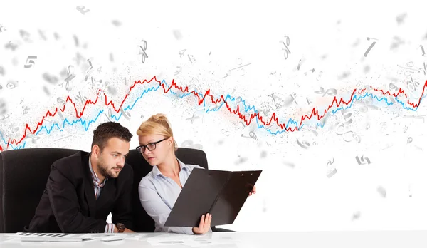 Business man and woman sitting at table with stock market graph — Stock Photo, Image