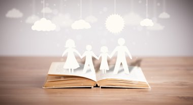 Ailenin karton figürleri açık bir kitabın üzerinde.