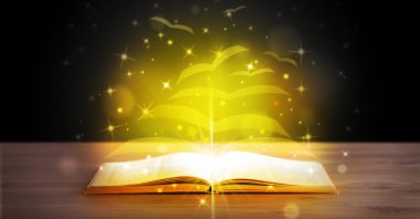 Altından parlak uçan kağıt sayfaları olan açık bir kitap