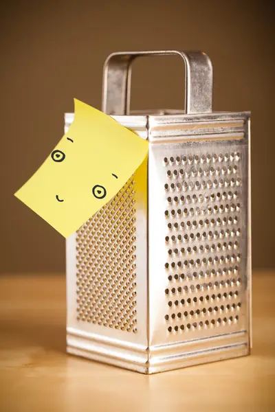 Post-it note with smiley face sticked on a grater — Stock Photo, Image