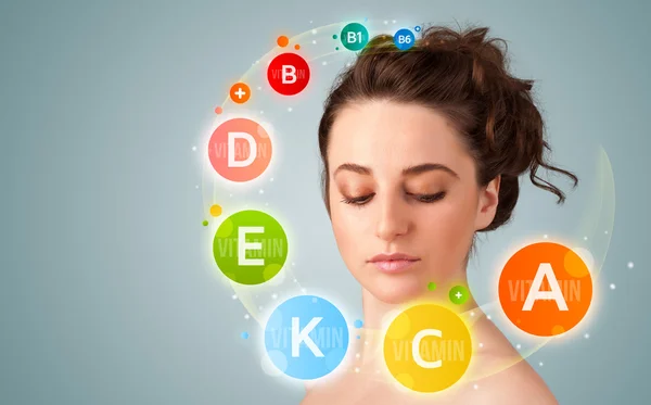 Pretty young girl with colorful vitamin icons and symbols — Stock Photo, Image