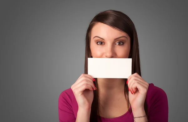 Niedliches Mädchen hält weiße Karte vor ihren Lippen mit Kopierschutz — Stockfoto