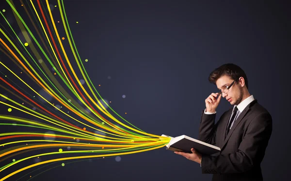 Hombre guapo leyendo un libro mientras líneas coloridas están saliendo —  Fotos de Stock