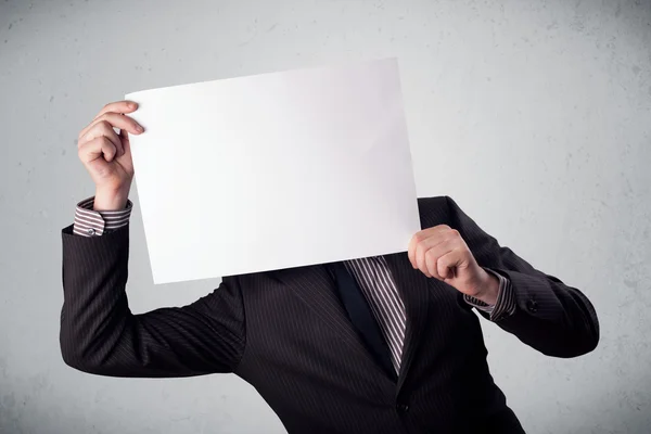 Businessman holding in front of his head a paper with copy space — Stock Photo, Image