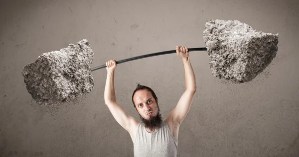 Skinny guy lifting large rock stone weights — Stock Photo, Image