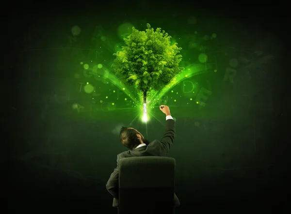 Businessman in chair sitting in front of a glowing tree — Stock Photo, Image