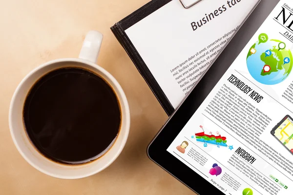Tablet pc shows news on screen with a cup of coffee on a desk — Stock Photo, Image