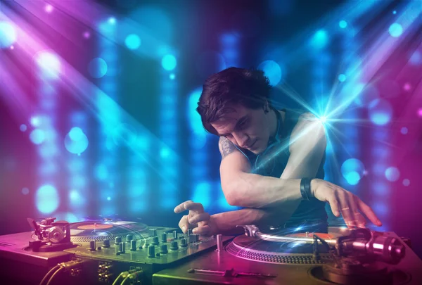 Dj mixing music in a club with blue and purple lights Stock Photo