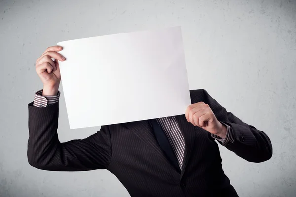 Businessman holding in front of his head a paper with copy space Stock Picture