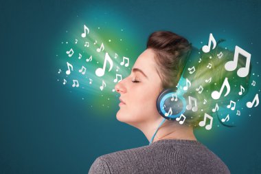 Kulaklıklı genç bir kadın müzik dinliyor.