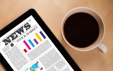 Tablet bilgisayarı haberleri ekranda bir fincan kahveyle sunar.