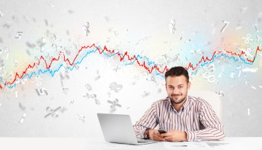 Borsa grafiğiyle masada oturan bir iş adamı