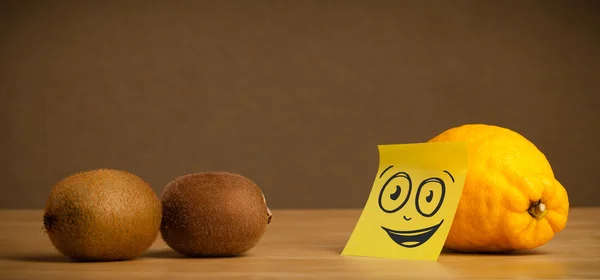 Lemon with post-it note watching at kiwis — Stockfoto