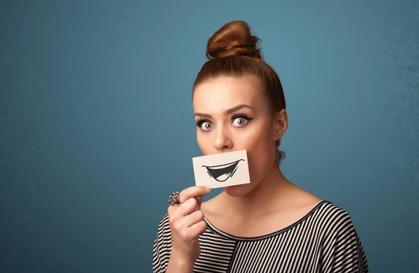 Felice ragazza carina in possesso di carta con divertente disegno smiley — Foto Stock