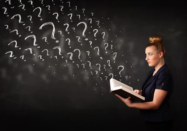 Pretty woman reading a book with question marks coming out from — Stock Photo, Image