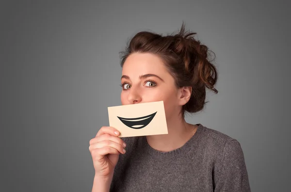 Feliz bonita mujer sosteniendo tarjeta con divertido smiley — Foto de Stock