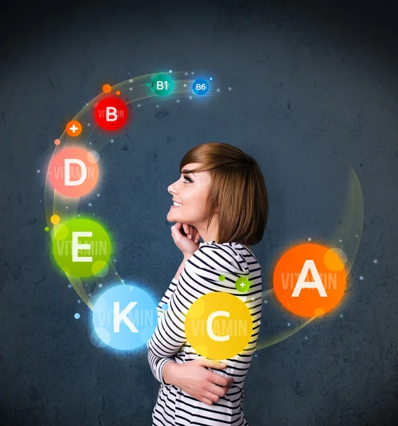 Young woman thinking with vitamins circulation around her head — Stock Photo, Image