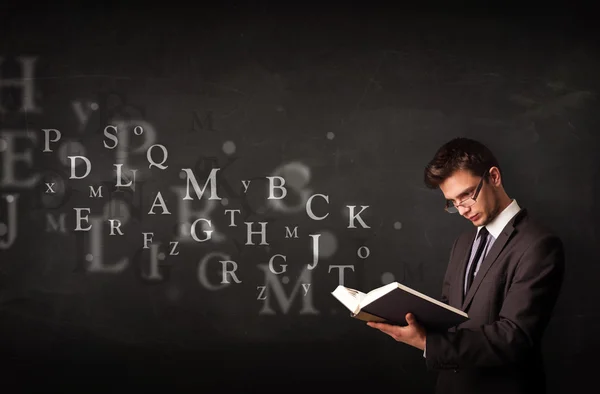 Молодой человек читает книгу буквами алфавита — стоковое фото