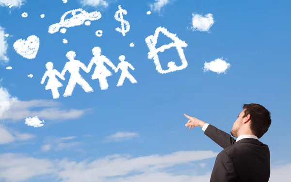 Businessman daydreaming with family and household clouds — Stock Photo, Image