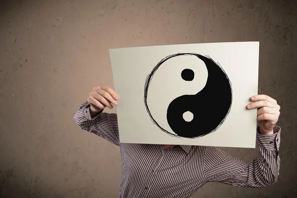 Businessman holding a paper with a yin-yang on it in front of hi — Stock Photo, Image