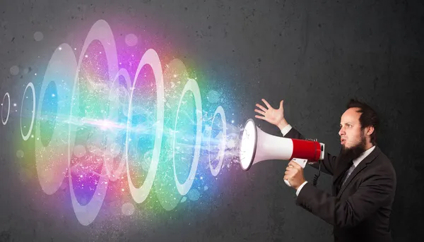 Man yells into a loudspeaker and colorful energy beam comes out — Stock Photo, Image