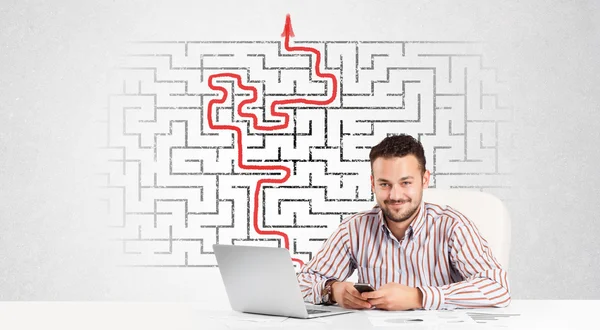 Business man at desk with labyrinth and arrow — Stock Photo, Image