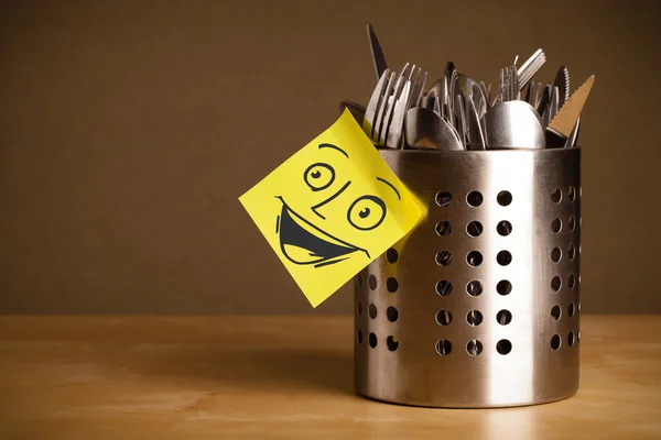 Post-it note with smiley face sticked on a cutlery case — Stock Photo, Image