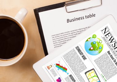 Tablet bilgisayarı haberleri ekranda bir fincan kahveyle sunar.