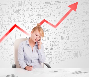Piyasa diyagramlarıyla masada oturan iş kadını.