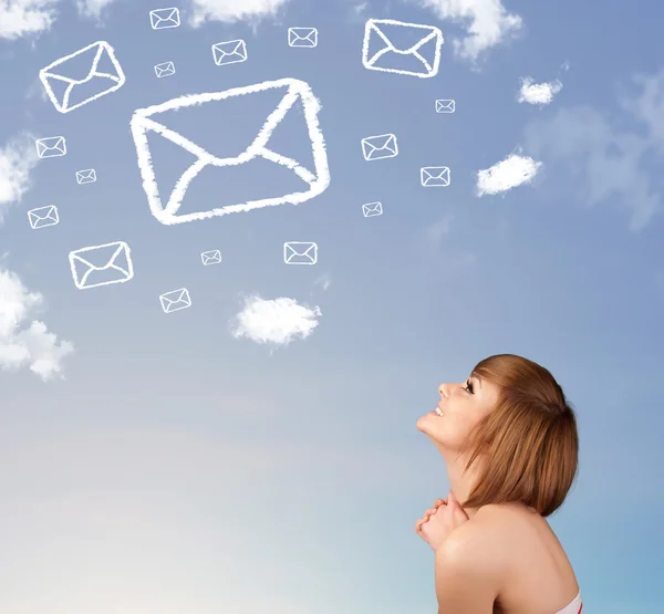 Chica joven mirando el símbolo de correo nubes en el cielo azul — Foto de Stock