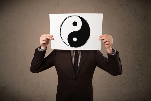 Empresario sosteniendo un papel con un yin-yang en frente de hi — Foto de Stock