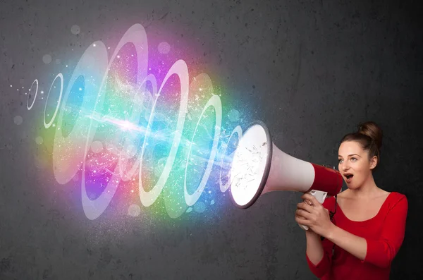 Young girl yells into a loudspeaker and colorful energy beam com — Stock Photo, Image