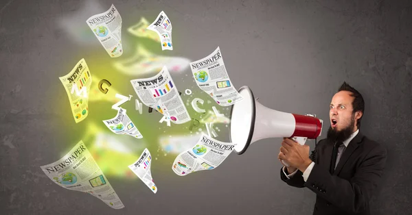 Guy yelling into loudspeaker and newspapers fly out — Stock Photo, Image