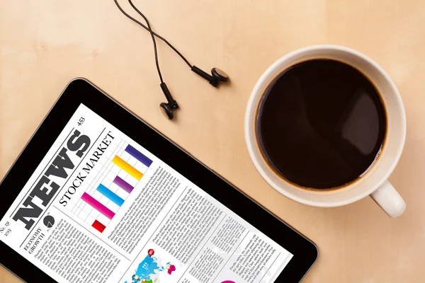 Tablet pc shows news on screen with a cup of coffee on a desk — Stock Photo, Image