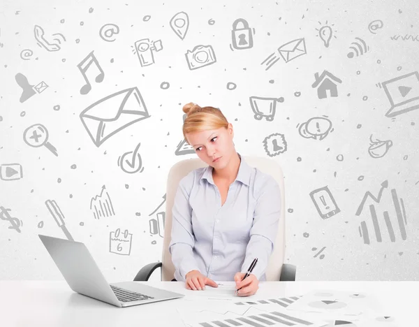 Mujer de negocios sentada a la mesa con iconos de medios dibujados a mano — Foto de Stock