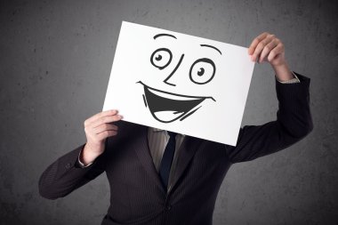 empresario sosteniendo una cartulina con cara sonriente en él en frente