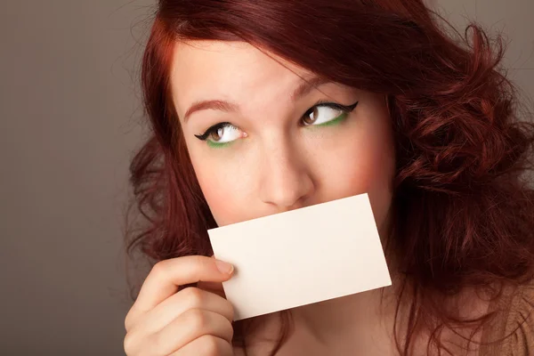 Menina bonito segurando cartão branco na frente de seus lábios com cópia spac — Fotografia de Stock