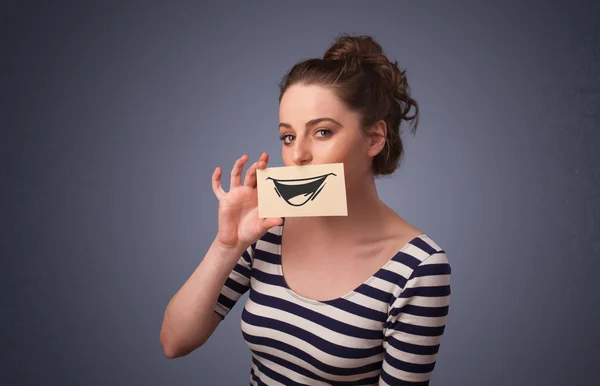 Счастливая симпатичная девушка держит в руках бумагу со смешным рисунком — стоковое фото